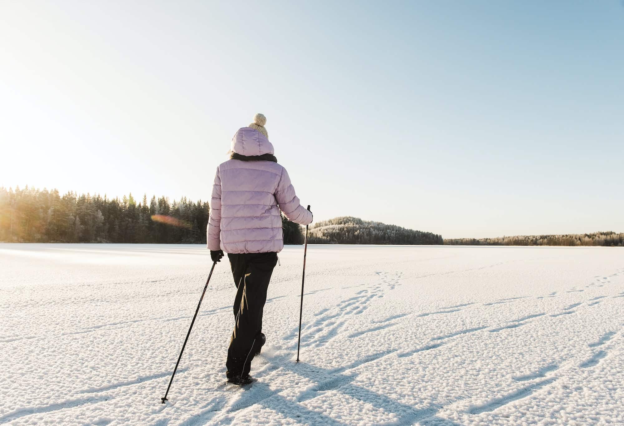 Woman nordic walking through snow covered field